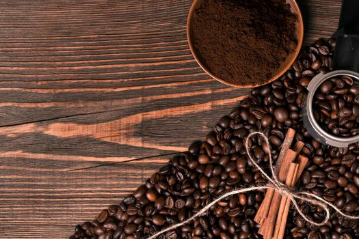 Ground coffee, coffee beans on wooden table background with cinnamon. Top view. Still life. Copy space. Flat lay.