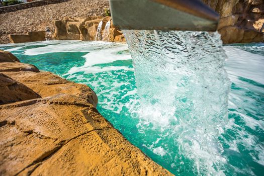 Stream of water out of artificial waterfall in outdoor pool at the luxury hotel in Egypt