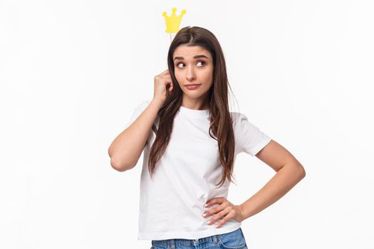 Entertainment, fun and holidays concept. Portrait of sassy and classy good-looking girl in t-shirt, holding carnaval stick with crown, acting like queen or super star, standing white background.