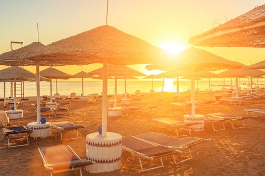 Beach with deck chairs and parasol at the luxury hotel during beautiful sunrise