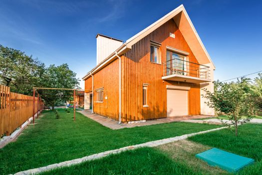 Beautiful wooden house with a lawn. Facade of traditional homes with grass in the foreground. at sunset and sunrise