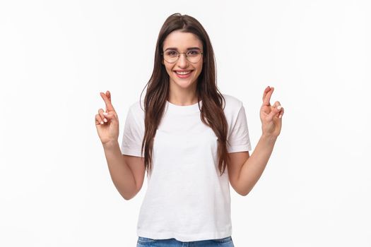 Waist-up portrait of optimistic girl believe dreams do come true, wear glasses and t-shirt, cross fingers good luck, make wish, praying and anticipating positive results, white background.