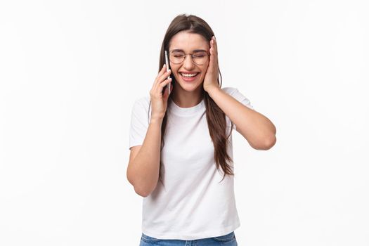 Communication, technology and lifestyle concept. Portrait of excited and happy, overwhelmed young caucasian woman receive excellent news, smiling and laughing, talking on mobile phone.