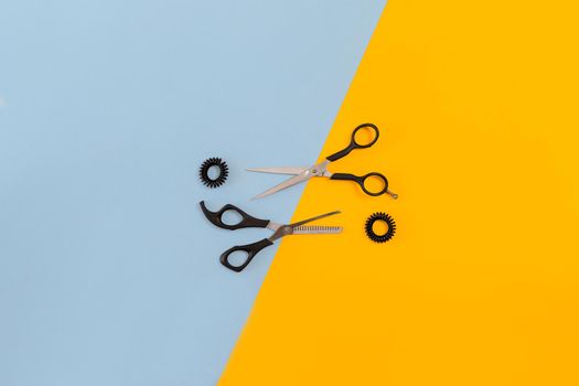 Scissors on the color blue, yellow paper background. Top view. Copy space. Still life. Mock-up. Flat lay