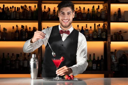 Young barman serving a cocktail at night club. High quality photo