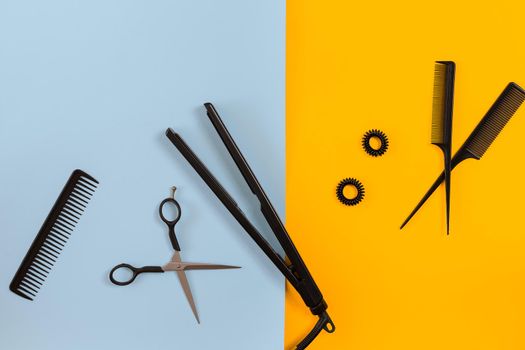 Various hair styling devices on the color blue, yellow paper background, top view. Copy space. Still life. Mock-up. Flat lay