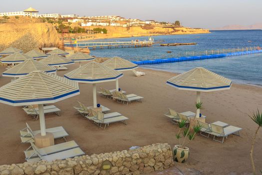 Beach with deck chairs and parasol at the luxury hotel during sunset