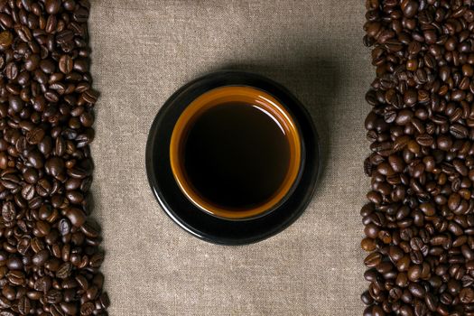 Coffee beans and Coffee cup on a burlap background. Top view. Copy space. Still life. Mock-up. Flat lay