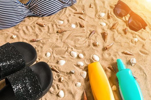 Summer bikini and accessories stylish beach set, Beach bikini summer outfit and sea sand as background, Top View, Concept. Copy space. Sun flare