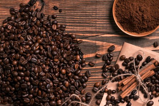 Coffee beans, cinnamon sticks and ground coffee on rustic wooden table, view from above with space for text. Still life. Mock-up. Flat lay