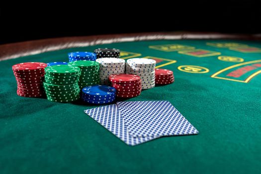 Poker play. Chips and cards on the green table