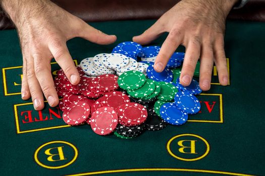 Poker play. Chips on the green table. chips in male hands