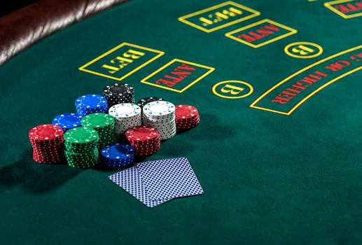 Poker play. Chips and cards on the green table