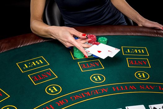 Poker play. Chips and cards on the green table. Cards in a player's hand. female hand throwing two aces. win