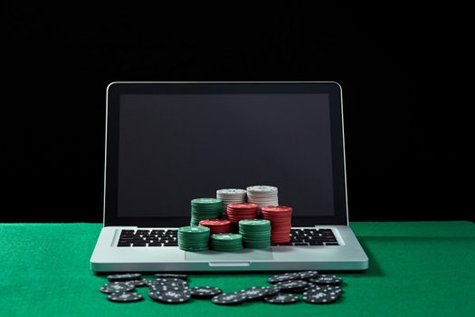 Image of casino chips on a keyboard notebook at green table. Concept for online gambling, poker, virtual casino.