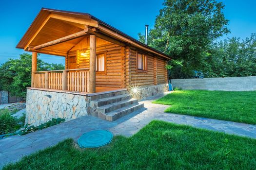 Beautiful wooden house with a lawn. Facade of traditional homes with grass in the foreground. Steam from a frame. at sunset and sunrise