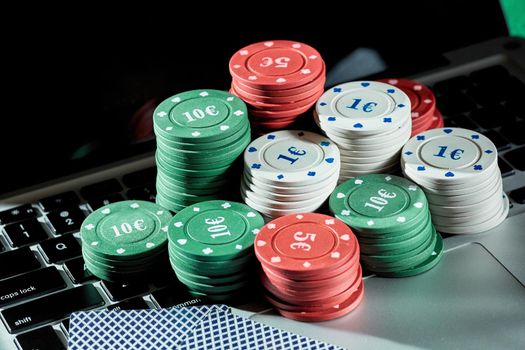 View of casino chips and cards on a laptop to play online. Concept for online gambling, poker, virtual casino.