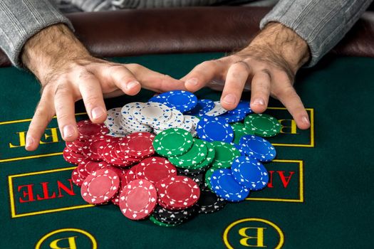 Poker play. Chips on the green table. chips in male hands