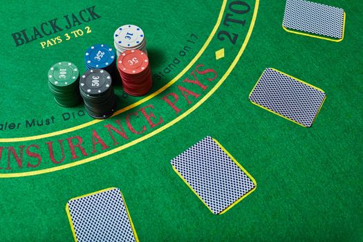 Casino chips and deck of cards lying on green casino table, poker game concept, top view.