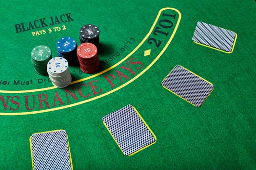 Casino chips and deck of cards lying on green casino table, poker game concept, top view.