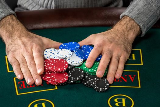 Poker play. Chips on the green table. chips in male hands