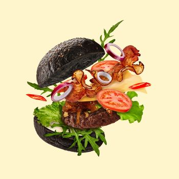Fresh black burger with flying ingredients on beige background. Ham, beef cutlet, cheese, sauces, vegetables and greens. Cooking, fast food. Unhealthy nutrition. Close up, copy space