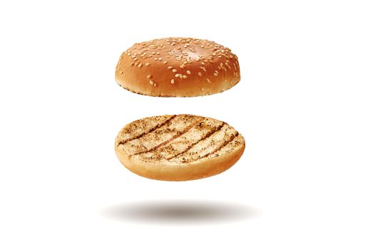 Flying, baked or grilled, cut in half burger bun with sesame seeds isolated on white background. Concept of cooking and fast food. Template, mock-up, advertising. Close-up, copy space