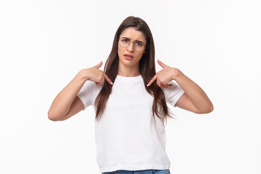 Waist-up portrait of insulted, shocked and offended young frustrated woman pointing at herself, grimace puzzled and confused, cant understand why she was picked or accused.
