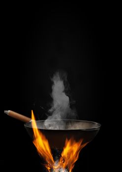 Empty wok pan with smoke above fire with sparks against black studio background. Cooking concept. Mockup, template for your collage, text or images. Advertising. Close up, copy space