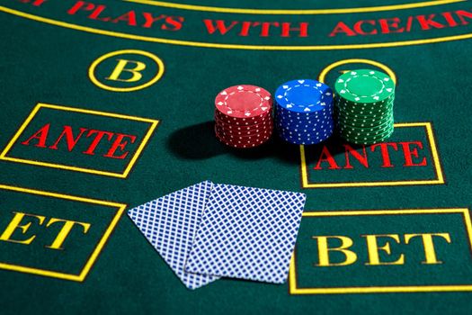 Poker play. Chips and cards on the green table