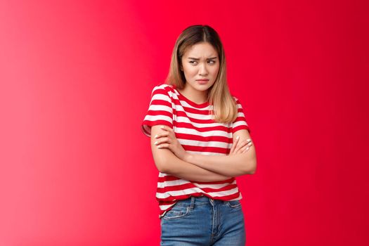 Upset timid insecure frowning asian blond girl feel offended, block insulted, cross arms chest disappointed offensive behaviour, stare left displeased moody jealous, stand red background unsatisfied.