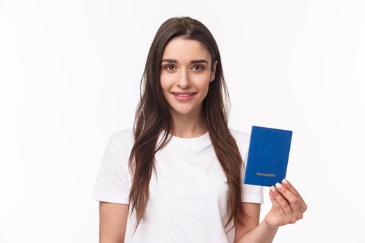 Travelling, holidays, summer concept. Close-up portrait of caucasian smiling happy woman in t-shirt, holding passport with and looking camera, buying flight ticket waiting for her plane in terminal.