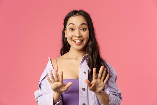 Close-up portrait of excited, cheerful asian girl made manicure, thanking master at nail salon, feel amazed and happy, looking at hands happy, fantastic job, standing pink background.