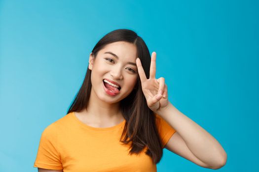 Close-up modern cute asian urban girl show tongue tilt head joyfully, express positive happy mood, make peace victory sign, smiling broadly, staying optimistic, excited participate lgbt pride.