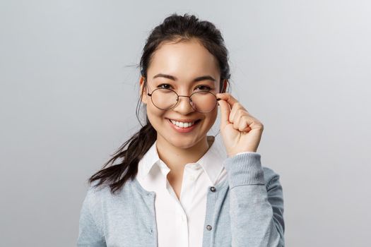 Advertisement, people and emotion concept. Close-up portrait of confident, professional asian brunette female, take-off glasses and look pleased camera, express satisfaction and self-assurance.