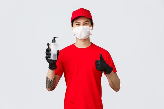 Carrier provide delivery workers with hand sanitisers, medical masks and gloves to protect from covid-19. Courier holding sanitiser and show thumb-up, assure clients their order is safe.