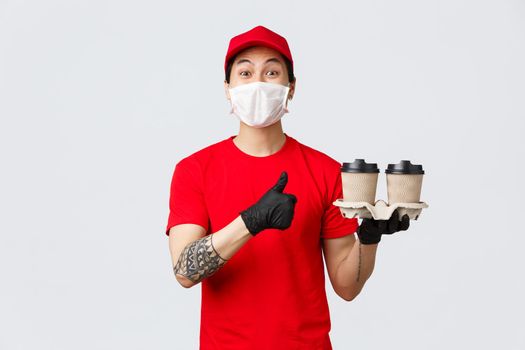 Your order is ready, best coffee in town. Smiling cheerful asian delivery man show thumb-up, deliver drinks to your house during pandemic covid 19, stay safe home and order online, recommend service.