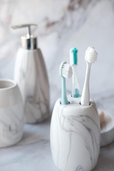 colorful toothbrushes in white mug against a wall .