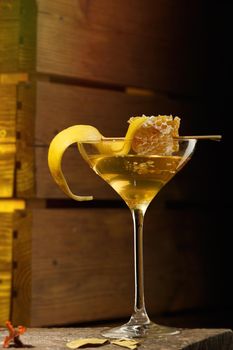 Honey and lemon vodka martini with a lemon twist and honeycomb decoration on a dark wood background