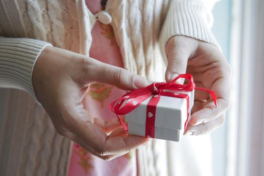 women hand holding small heart shape gift box .