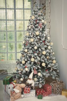 Christmas, New Year interior with gray wall background, decorated fir tree with garlands and balls, teddy bear and presents