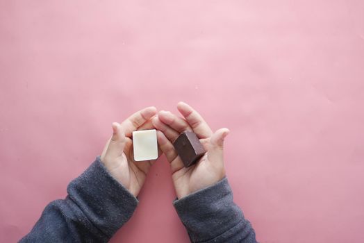 child holding dark and white chocolate on pink .