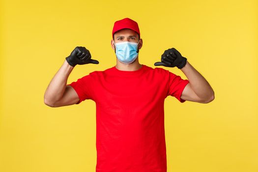 Express delivery during pandemic, covid-19, safe shipping, online shopping concept. Confident and determined courier in red uniform, medical mask, pointing himself serious, hero deliver order.