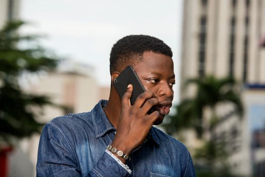 young african man standing in jeans going to communicate in the street.
