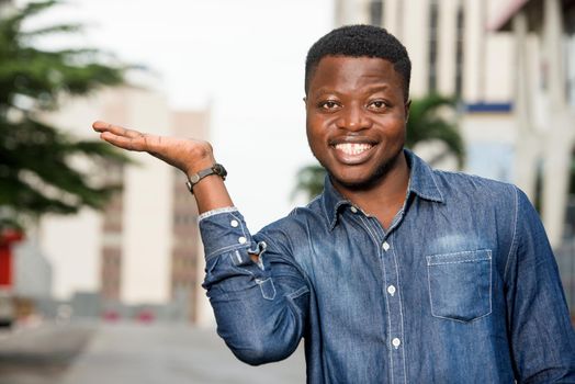 portrait of young happy man in shirt gesturing a welcome sign showing something of the hand
