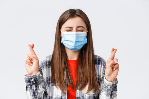 Coronavirus outbreak, leisure on quarantine, social distancing and emotions concept. Close-up of hopeful, dreamy young girl making wish, close eyes and cross fingers good luck.