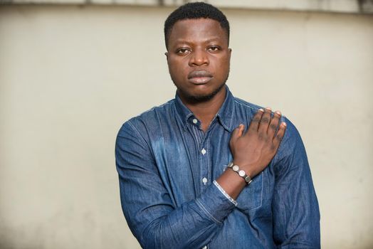 young african man standing in jeans shirt looking at the camera.