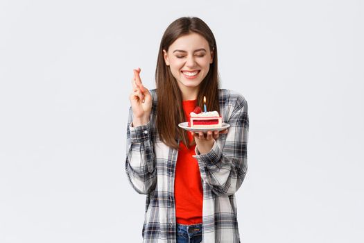 People lifestyle, holidays and celebration, emotions concept. Happy, cheerful b-day girl celebrating, close eyes cross fingers as blowing candle to make wish on birthday cake.