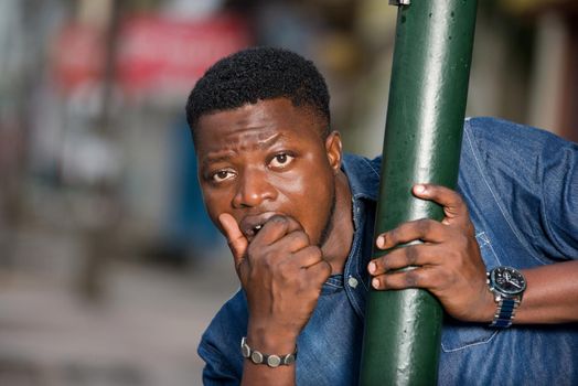 young african man behind iron bar looking at the camera, surprised.
