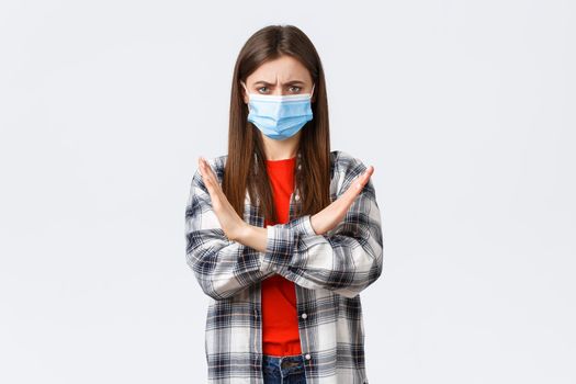 Coronavirus outbreak, leisure on quarantine, social distancing and emotions concept. Enough, this should stop. Serious displeased young woman in medical mask protest, show cross sign.